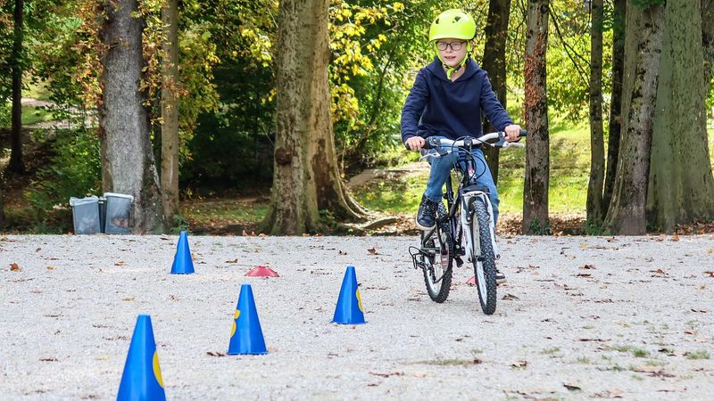 un jeune enfant fait du vélo entre des plots posés au sol