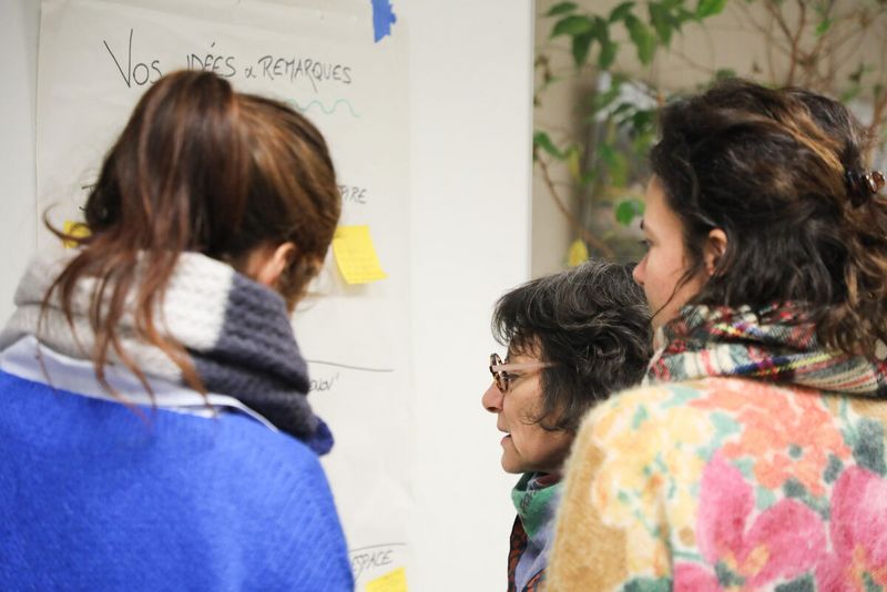 Trois personnes échangent devant un tableau qu'elles annotent