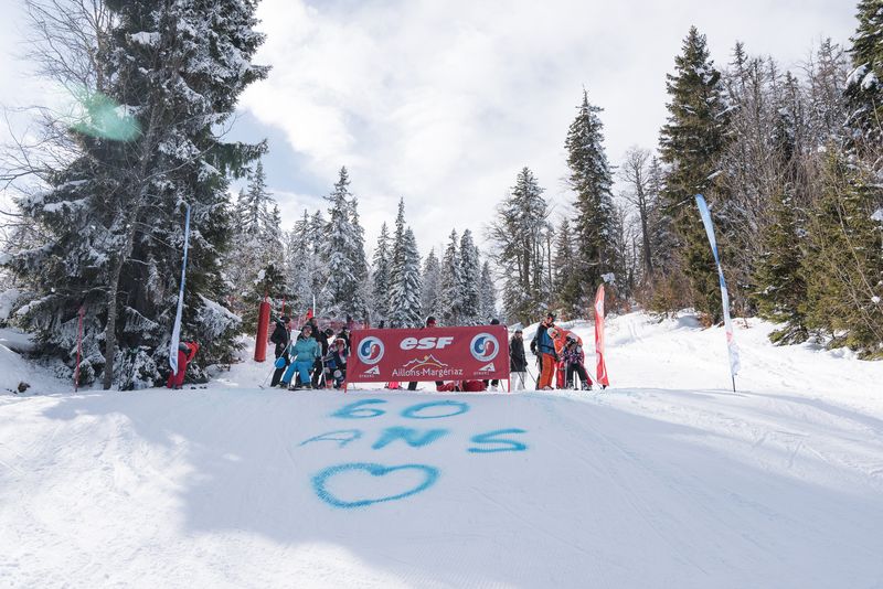 photo d'un groupe de personnes sur une piste de ski enneigée où est tagué à la bombe bleue sur la neige 60 ans