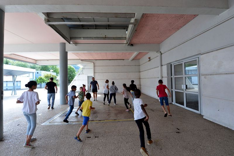 des jeunes jouent au ballon dans une cour d'école