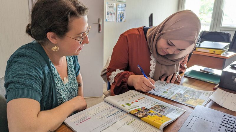 Une femme apprend à une autre femme adulte à lire et écrire le français