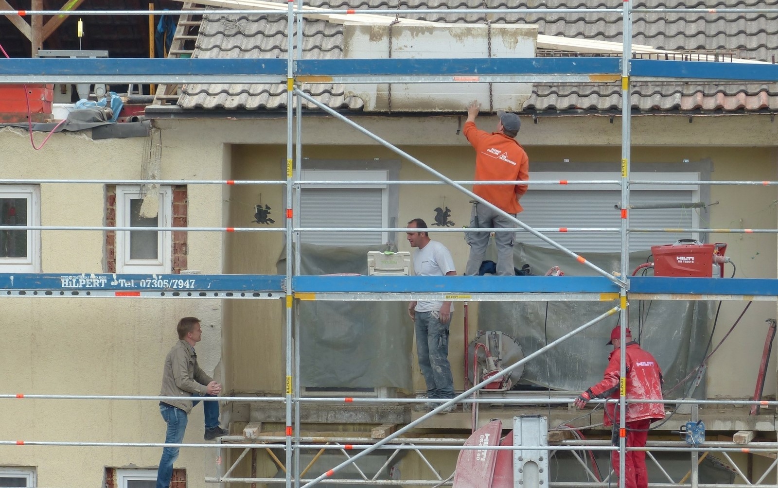 Photo de professionnels du bâtiment rénovant une façade d'une maison.